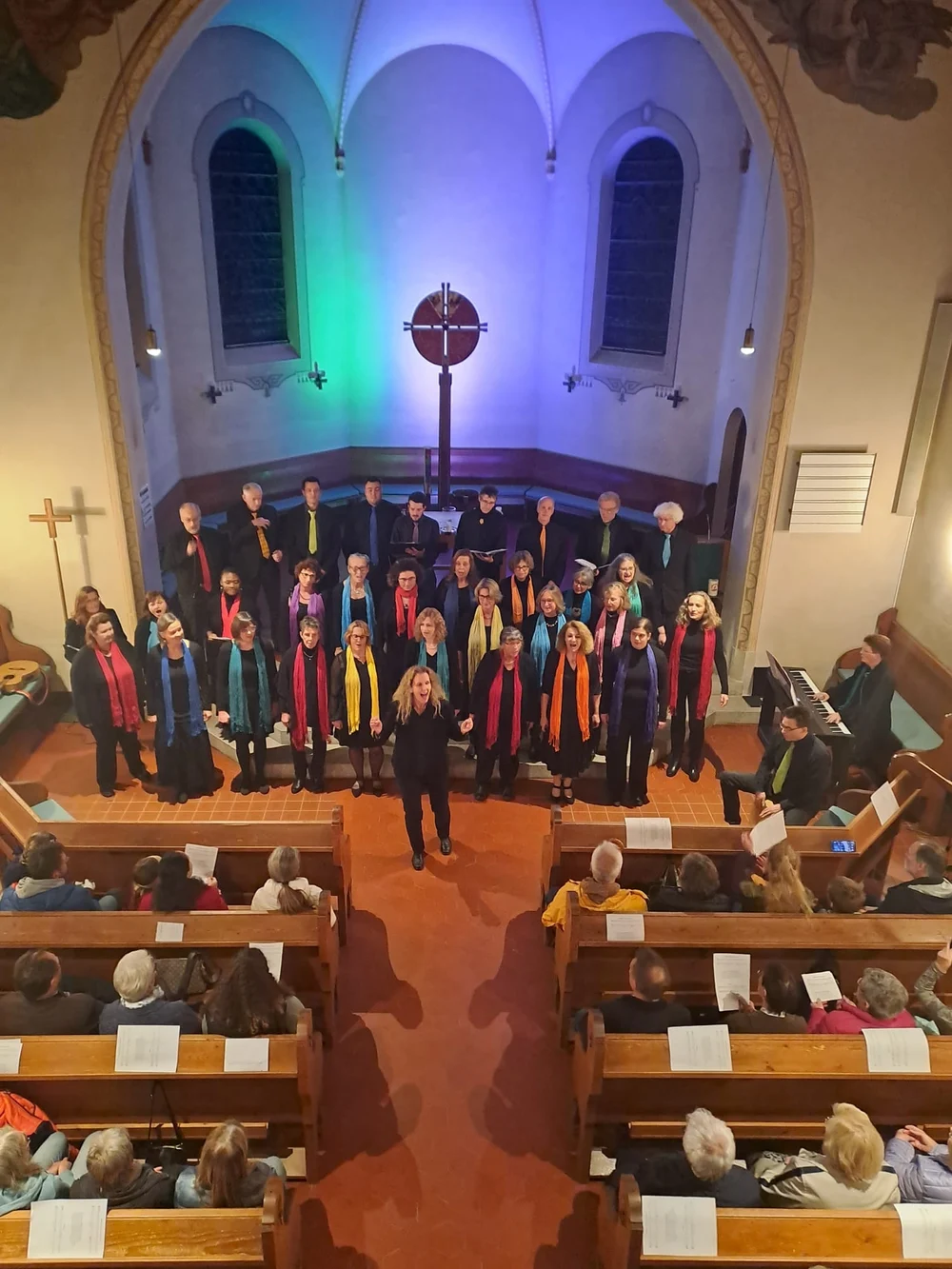 Die Rainbow Gospel Voices singen in der Kirche; Blick von der Empore auf Chor, Instrumente und Publikum.